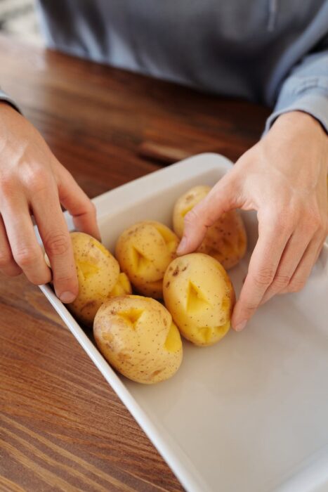Person Holding a White Tray With Potatoes