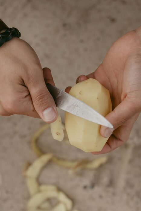 Person Peeling A Potato With A Knife