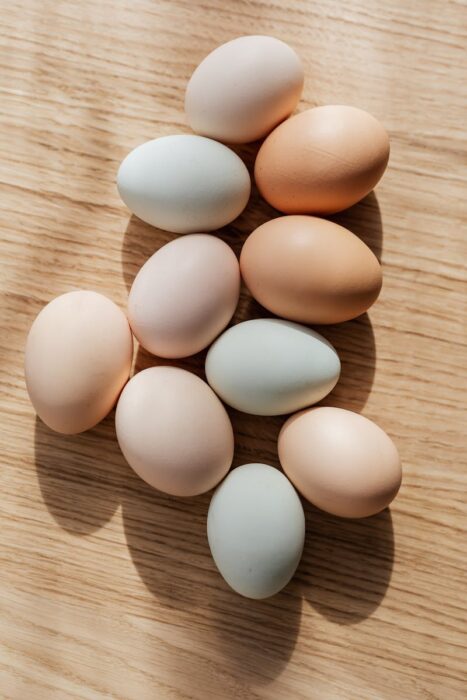 Top view composition of various organic chicken eggs placed on wooden background in daylight